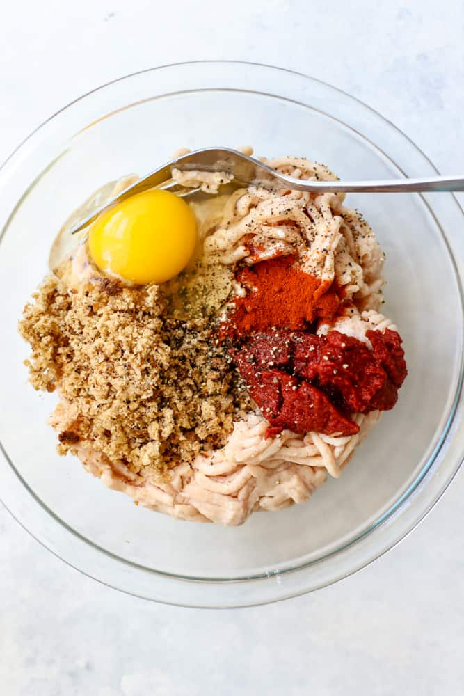 Ground chicken, breadcrumbs, egg, spices, and tomato paste in clear bowl and not mixed together yet