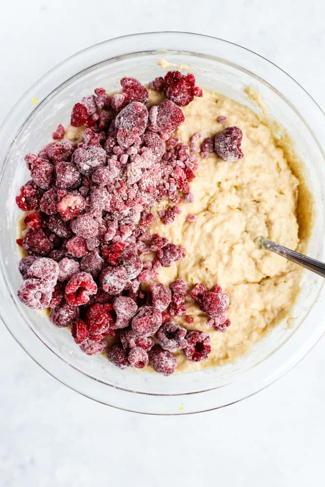 Raspberries tossed in flour, added to muffin mixture in clear glass bowl