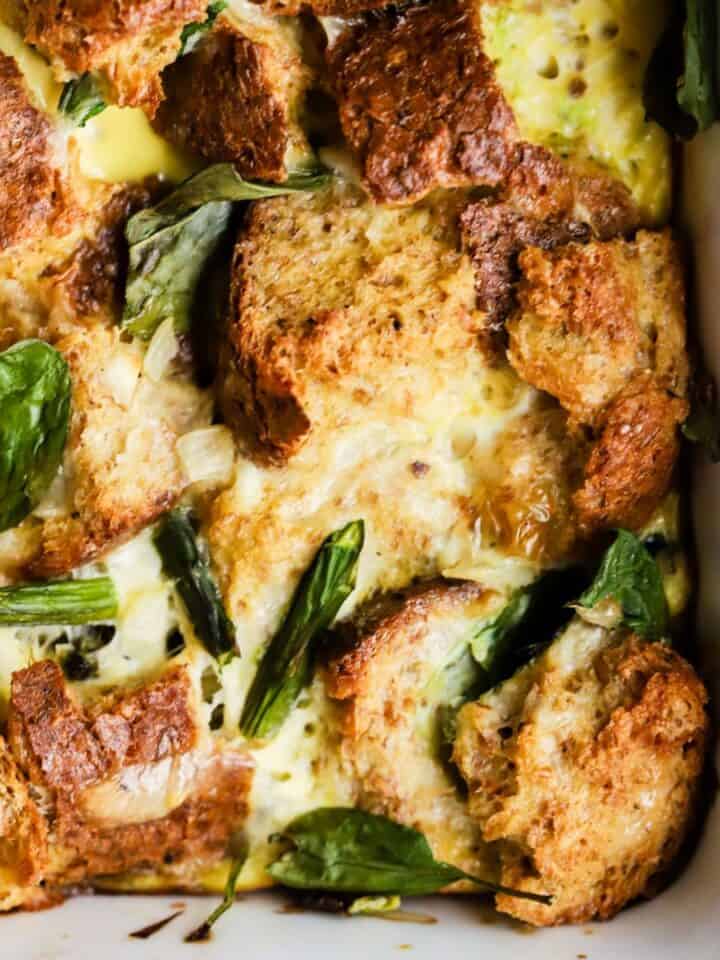 Spring veggie breakfast strata baked in white ceramic baking dish.