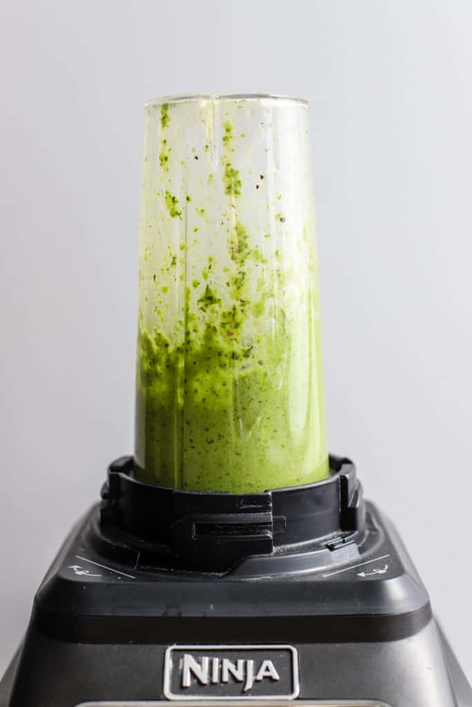 Homemade basil vinaigrette in a blender after being fully blended