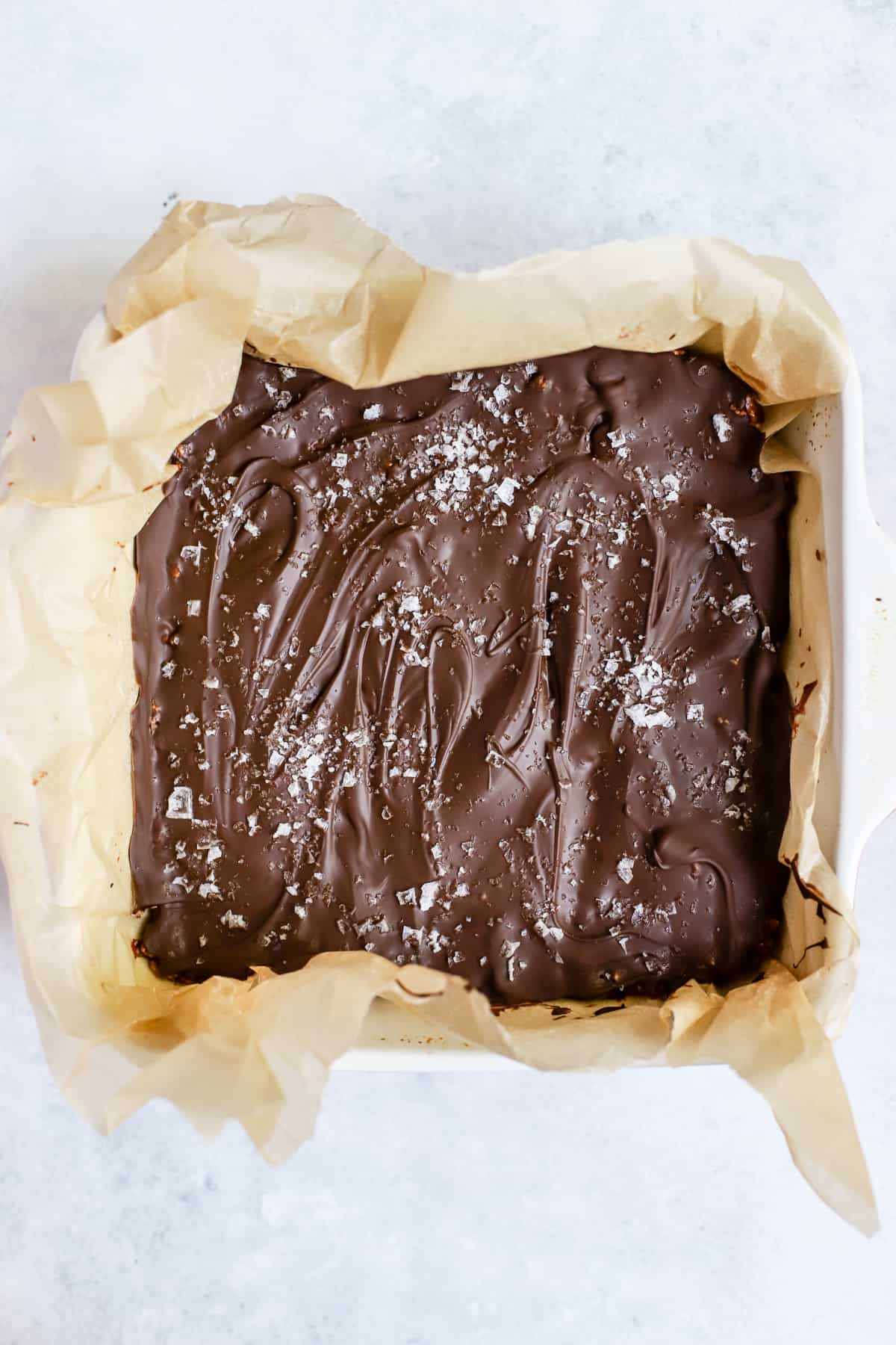Healthy scotcheroos batch in baking pan with flaky salt sprinkled on top.