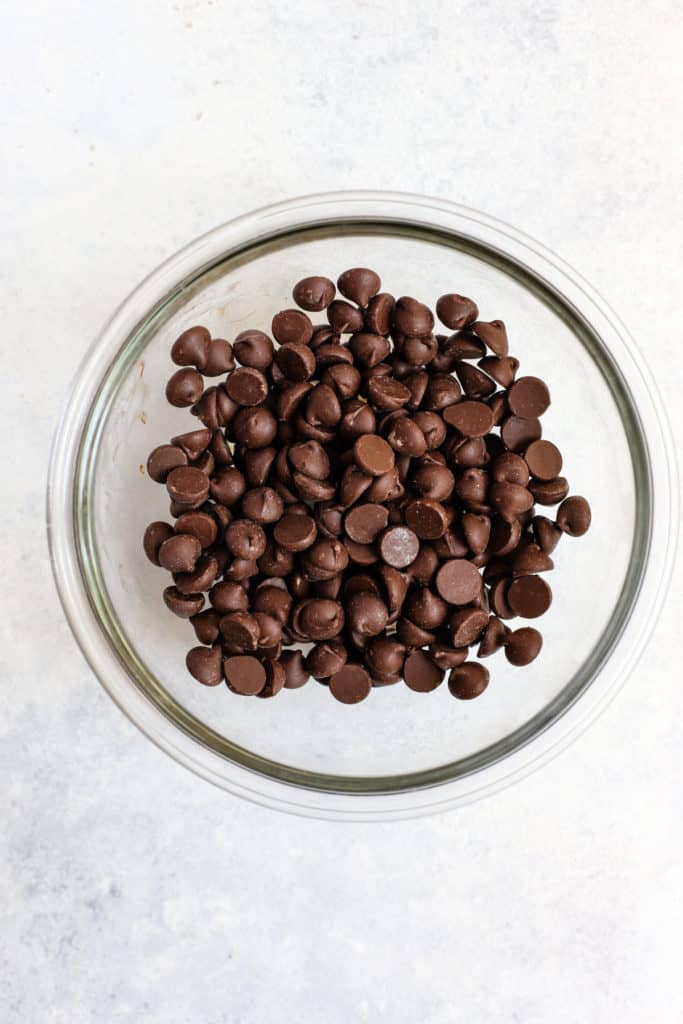 Dark chocolate chips in small clear glass bowl