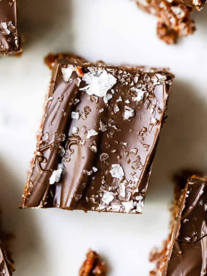 Healthy scotcheroos topped with flaky sea salt and cut into squares on blue and white background