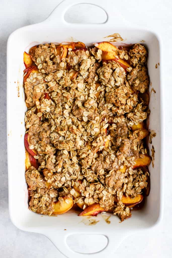 Baked healthy peach crisp in white ceramic baking dish