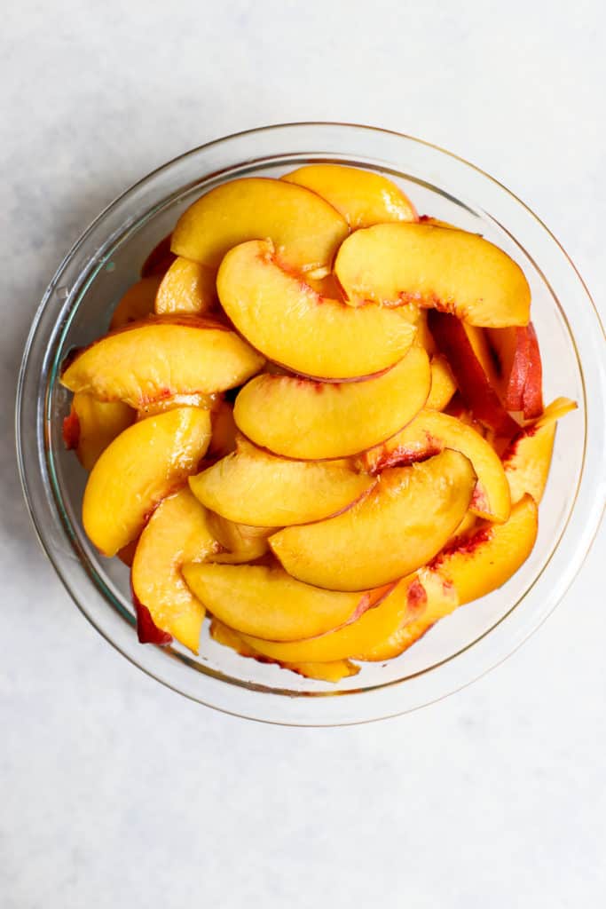 Thinly sliced fresh peaches in clear glass bowl