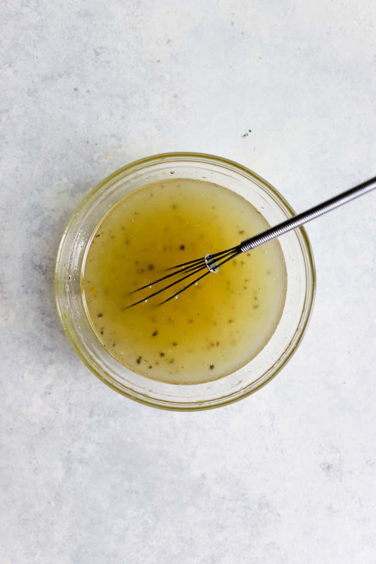 Apple cider vinegar mixture in small glass bowl with small whisk