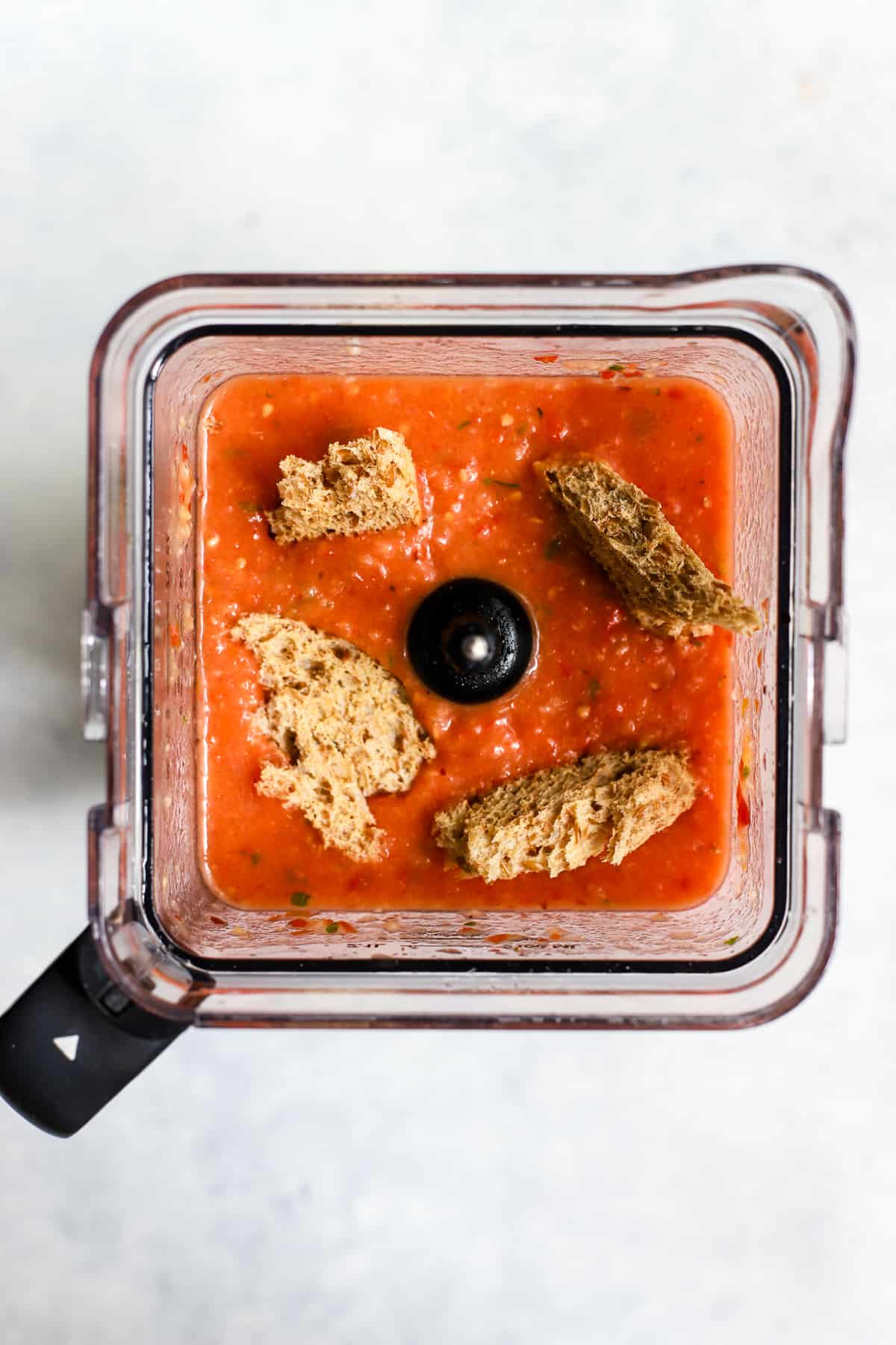 Peach basil gazpacho in blender with bread chunks dipped in