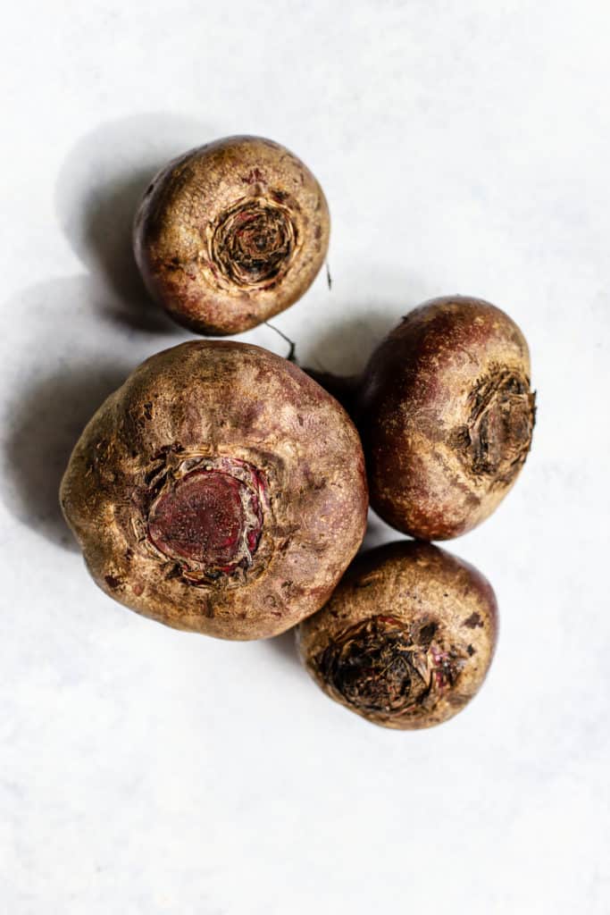 Whole beets on light blue and white surface