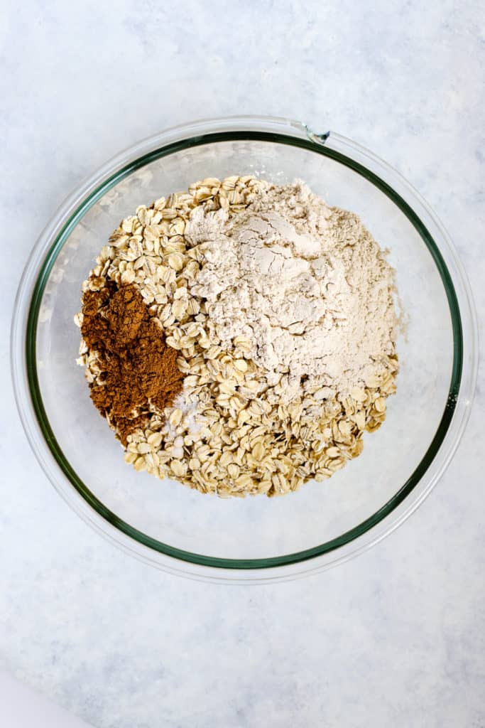 Oats, whole wheat flour, pumpkin pie spice, and salt in clear glass bowl
