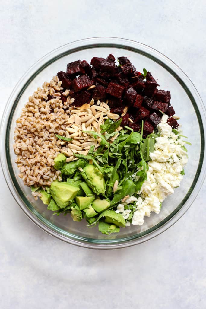 Roasted beet and avocado salad ingredients in large clear glass bowl