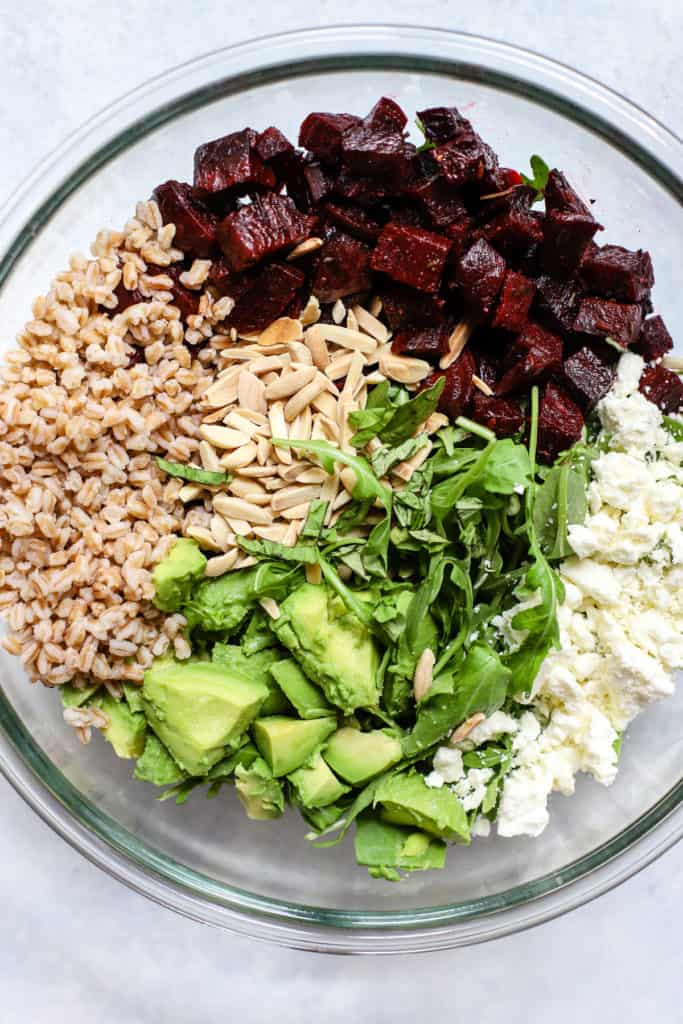 Roasted beet and avocado salad ingredients in large clear glass bowl