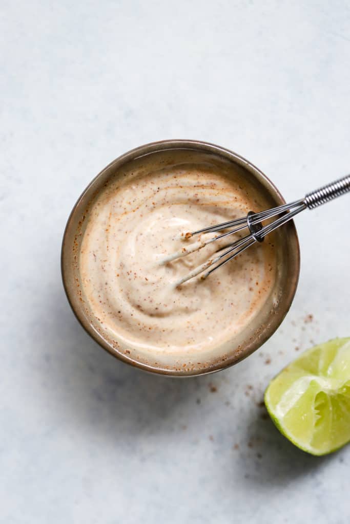 Chipotle mayo in small gray pinch bowl with mini whisk, and lime wedge on the side