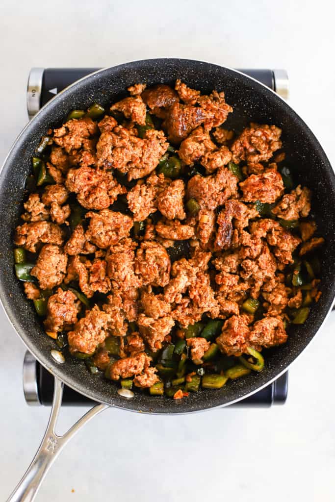 Sautéed chorizo, poblano peppers, and garlic in black sauté pan