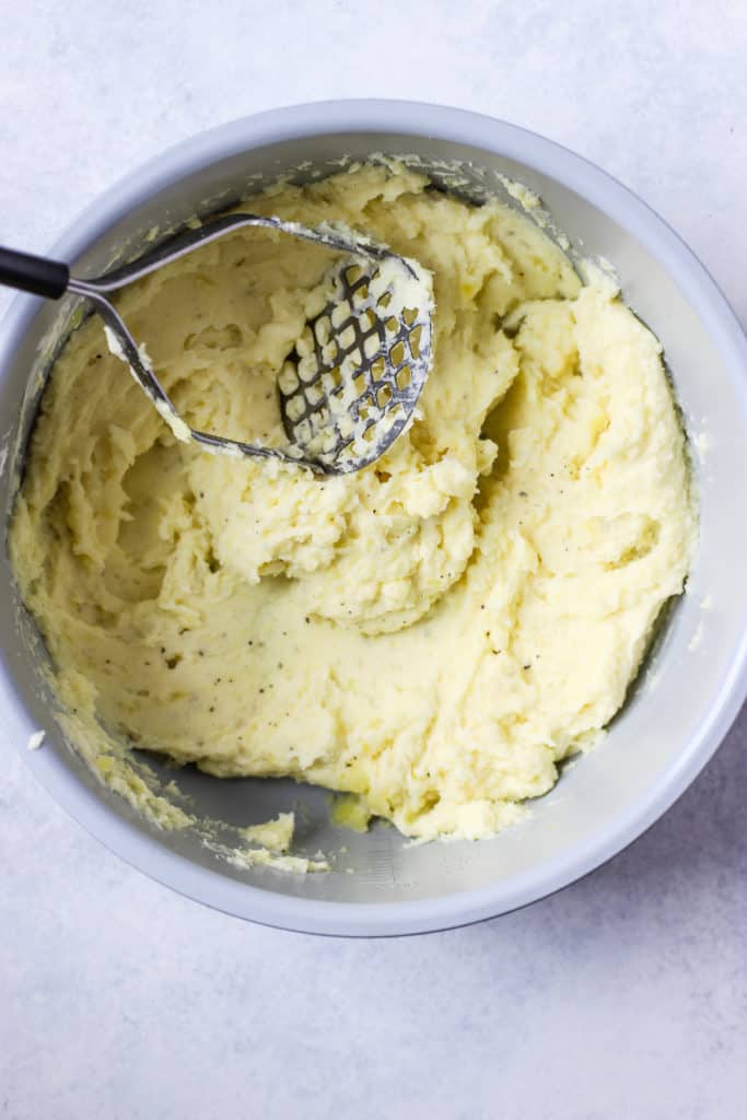 Mashed potatoes in base of pressure cooker, with potato masher