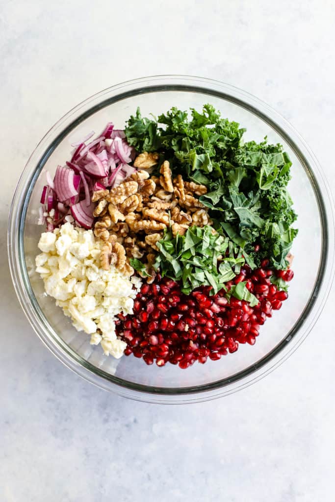 All wild rice and pomegranate salad ingredients in clear glass bowl, before being mixed