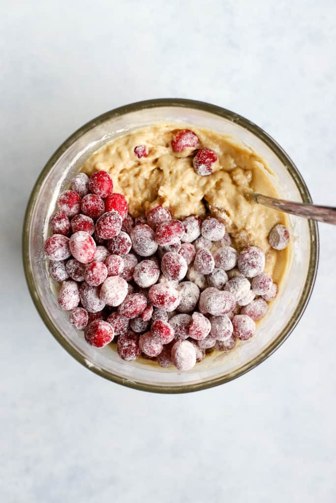 Whole fresh cranberries poured onto bowl of cranberry orange muffin batter, before being stirred in