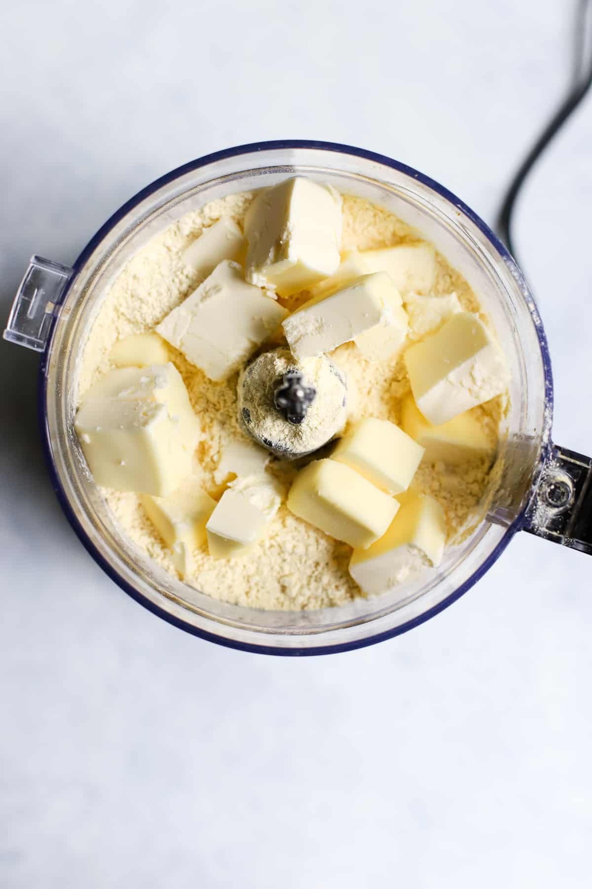 Frozen butter cubes added to chickpea (gram) flour mixture, in food processor.