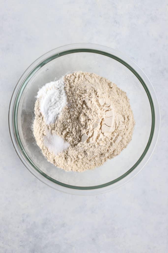 White whole wheat flour, salt, baking soda, and baking powder in a clear glass bowl