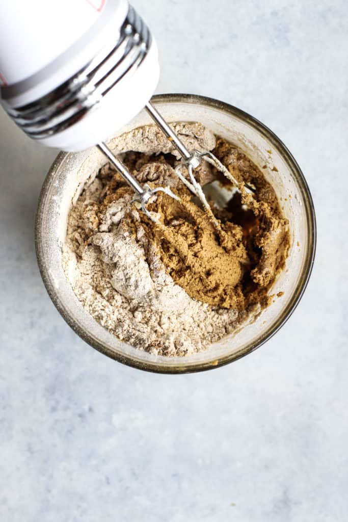 Soft ginger molasses cookies dry ingredients being mixed into wet ingredients with hand mixer