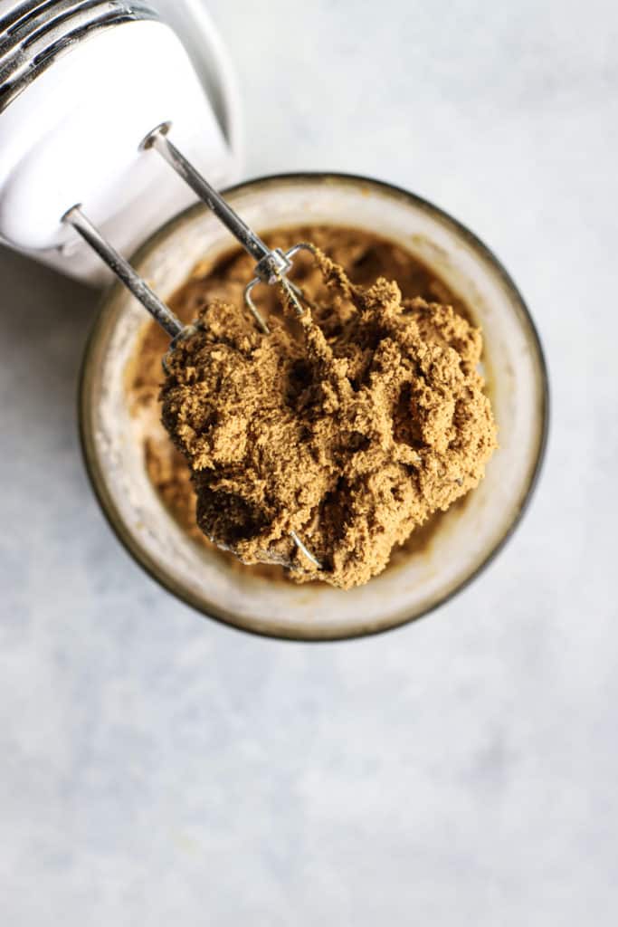 Soft ginger molasses cookie dough on hand mixer beaters, resting over glass bowl