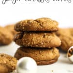 A stack of three healthier soft ginger molasses cookies, with more cookies in the background, on white marble surface with a few ornaments