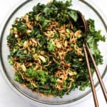 Healthy Asian slaw with ramen in clear glass bowl with two copper serving spoons