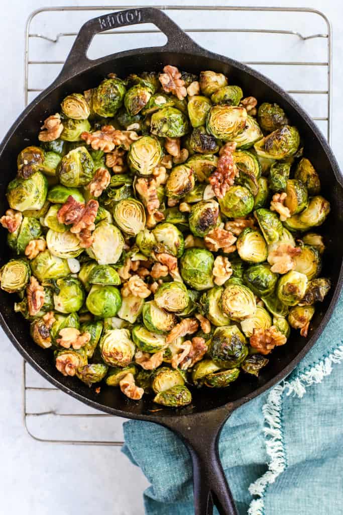 Roasted Brussels sprouts with maple & walnuts in a black cast iron skillet.