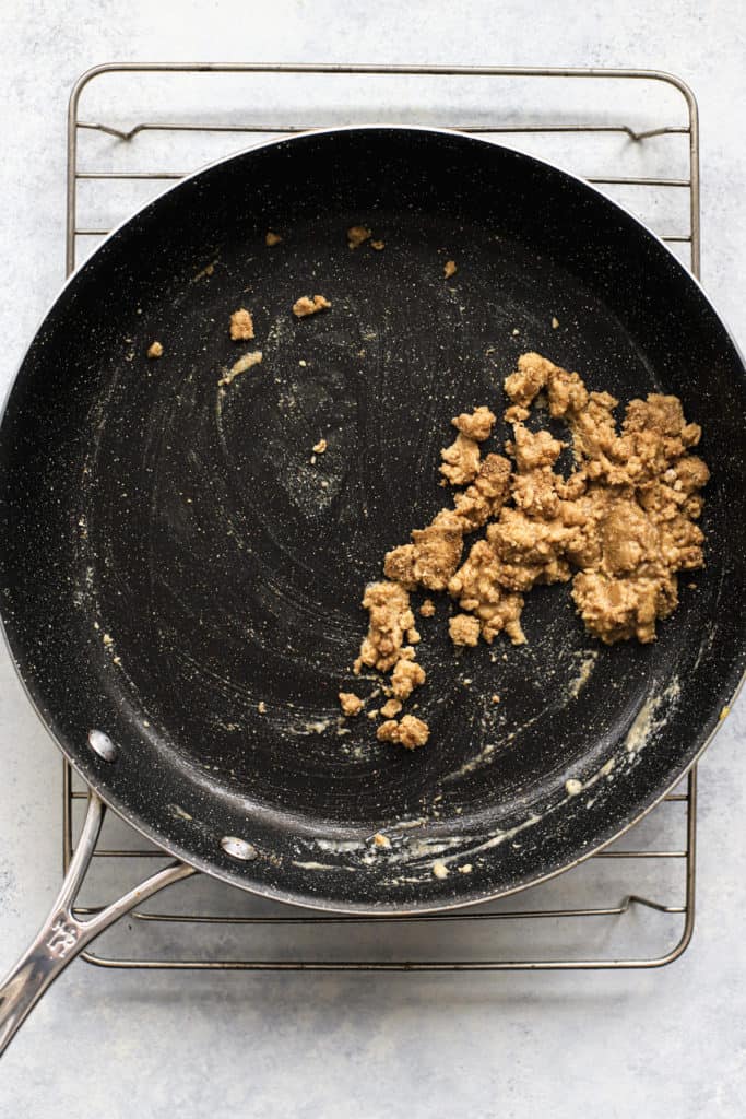 Flour, coriander, and salt mixture added to melted butter to make the base of the white enchilada sauce, in dark skillet on wire cooling rack