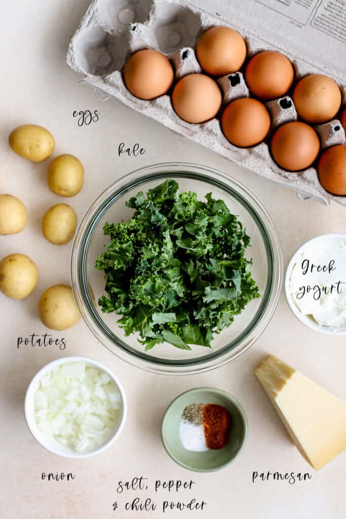 Frittata ingredients, including kale, eggs, potatoes, onions, salt, pepper, chili powder, parmesan, and Greek yogurt.