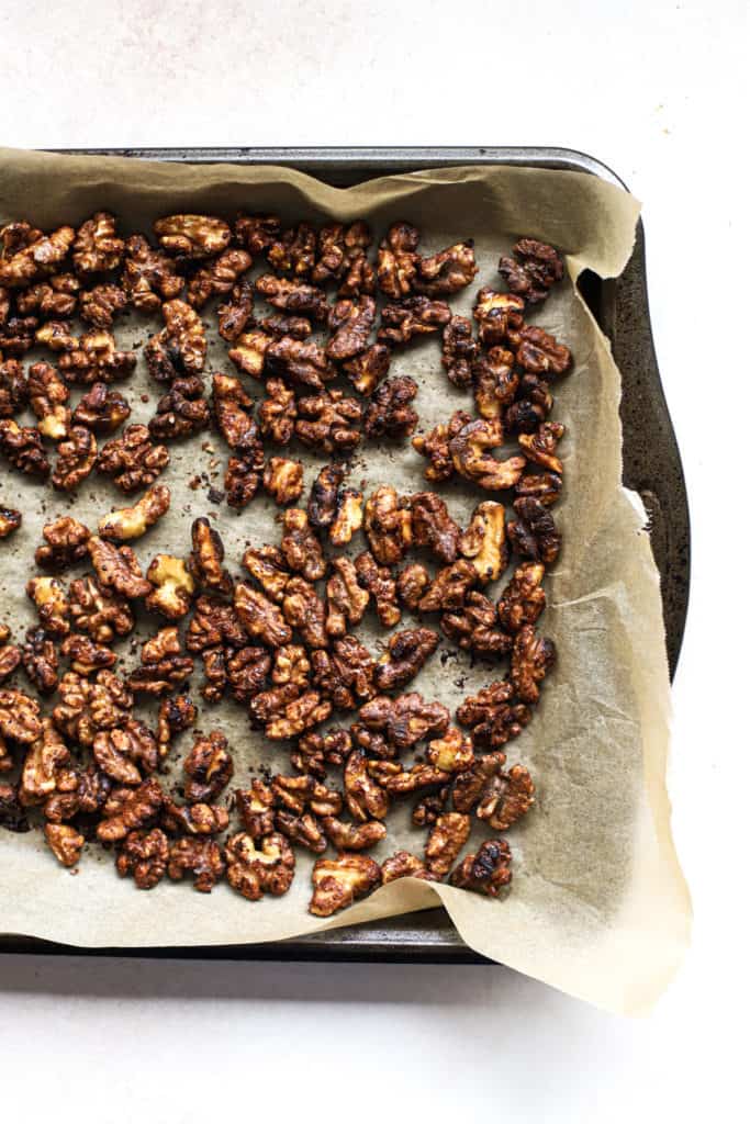 Cayenne maple toasted walnuts on parchment lined baking sheet.