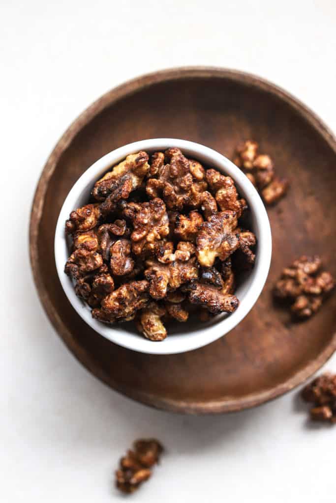 Maple cayenne toasted walnuts in small white bowl.