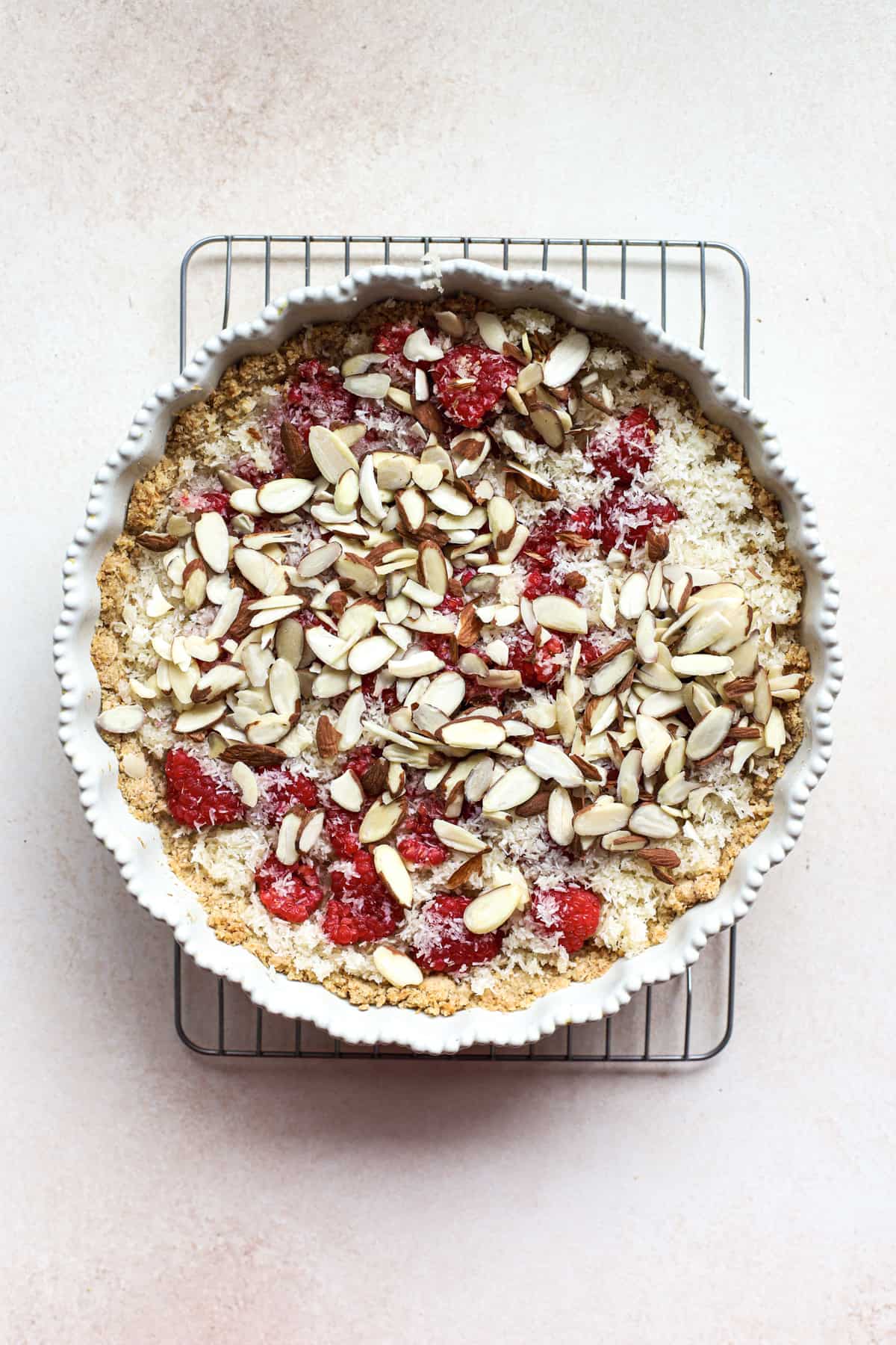 Macaroon crust filling with coconut macaroon filling, fresh raspberries, and topped with sliced almonds before baking