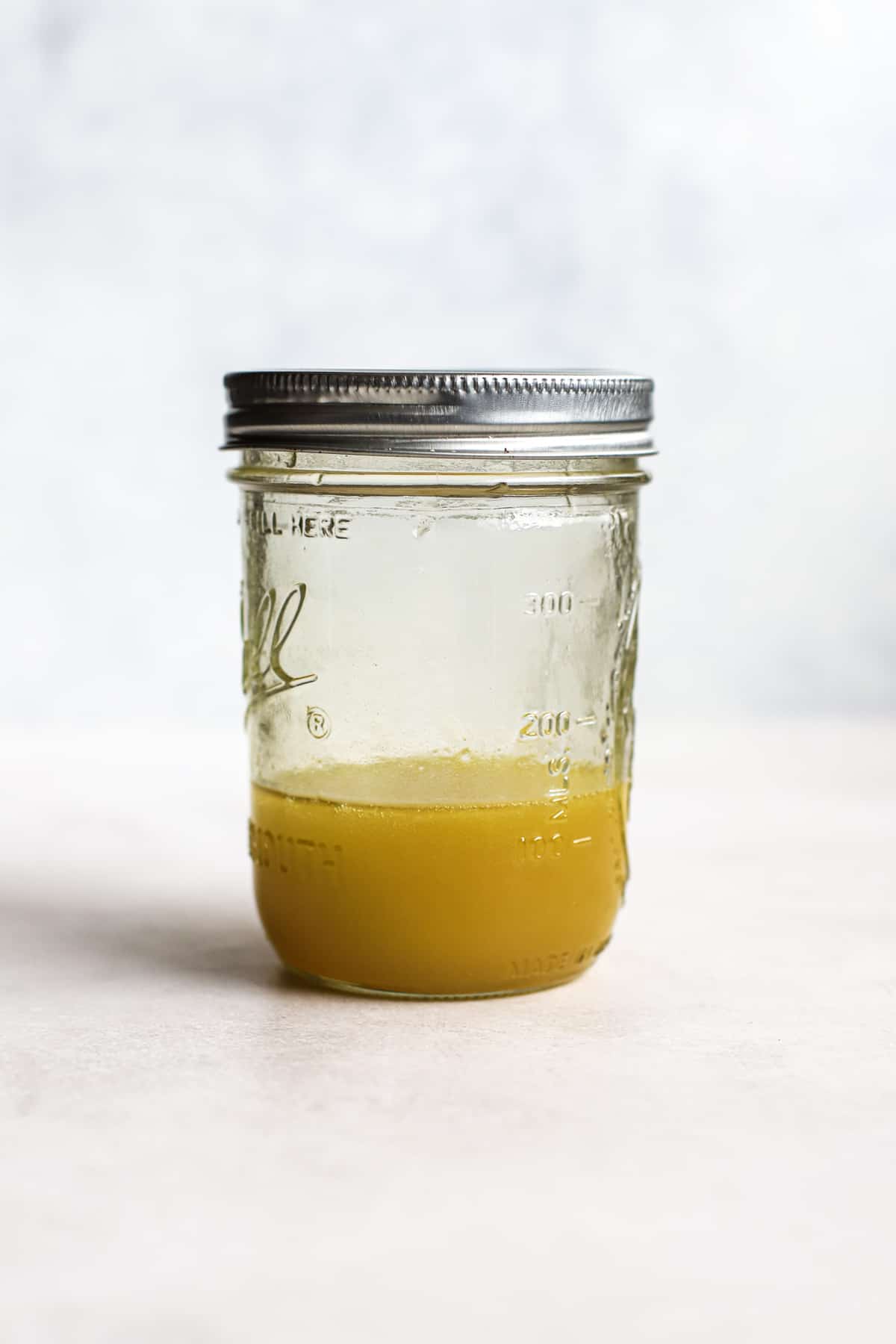 Coleslaw vinaigrette in mason jar on light gray surface.