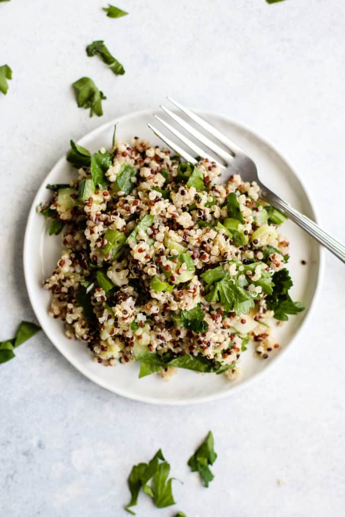 Simple detox quinoa salad on small white plate with fork.