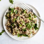 Simple detox quinoa salad on small white plate with fork