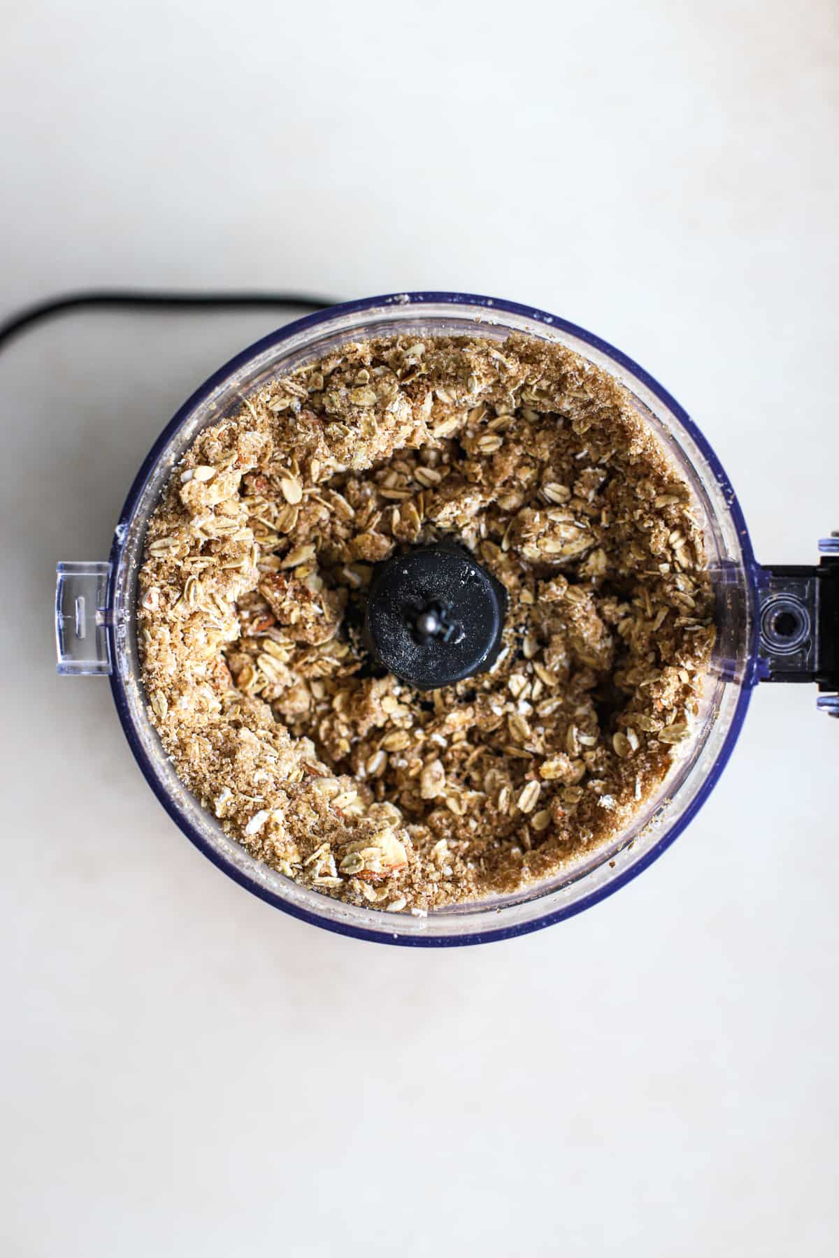 Strawberry crisp topping in food processor on beige and white surface