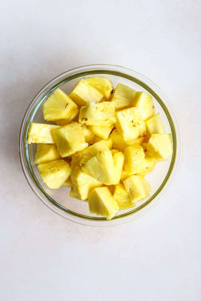 Fresh pineapple chunks in clear glass bowl, after using our "how to cut a pineapple" method