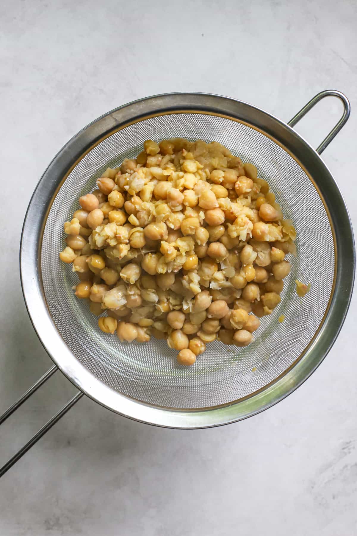 Cooked chickpeas draining in metal strainer.