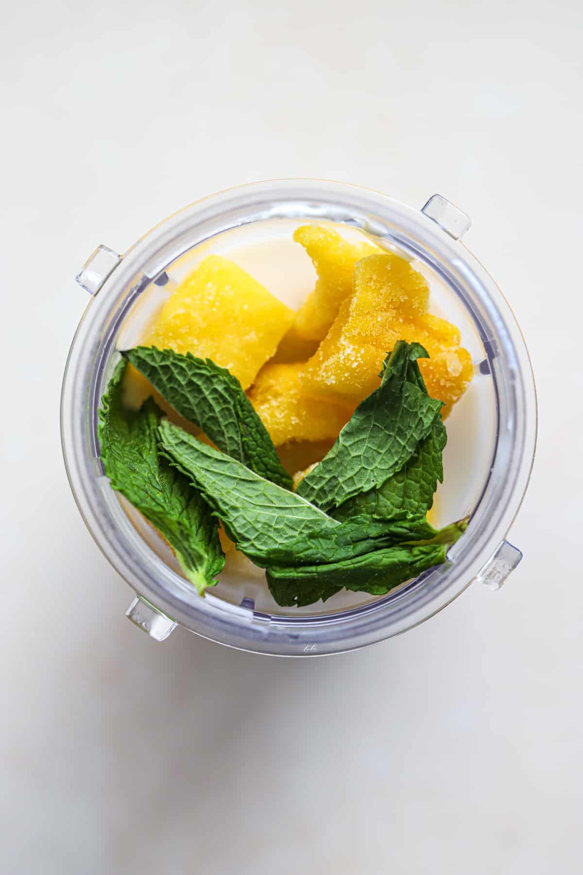 Frozen mango, milk, yogurt, and fresh mint in blender