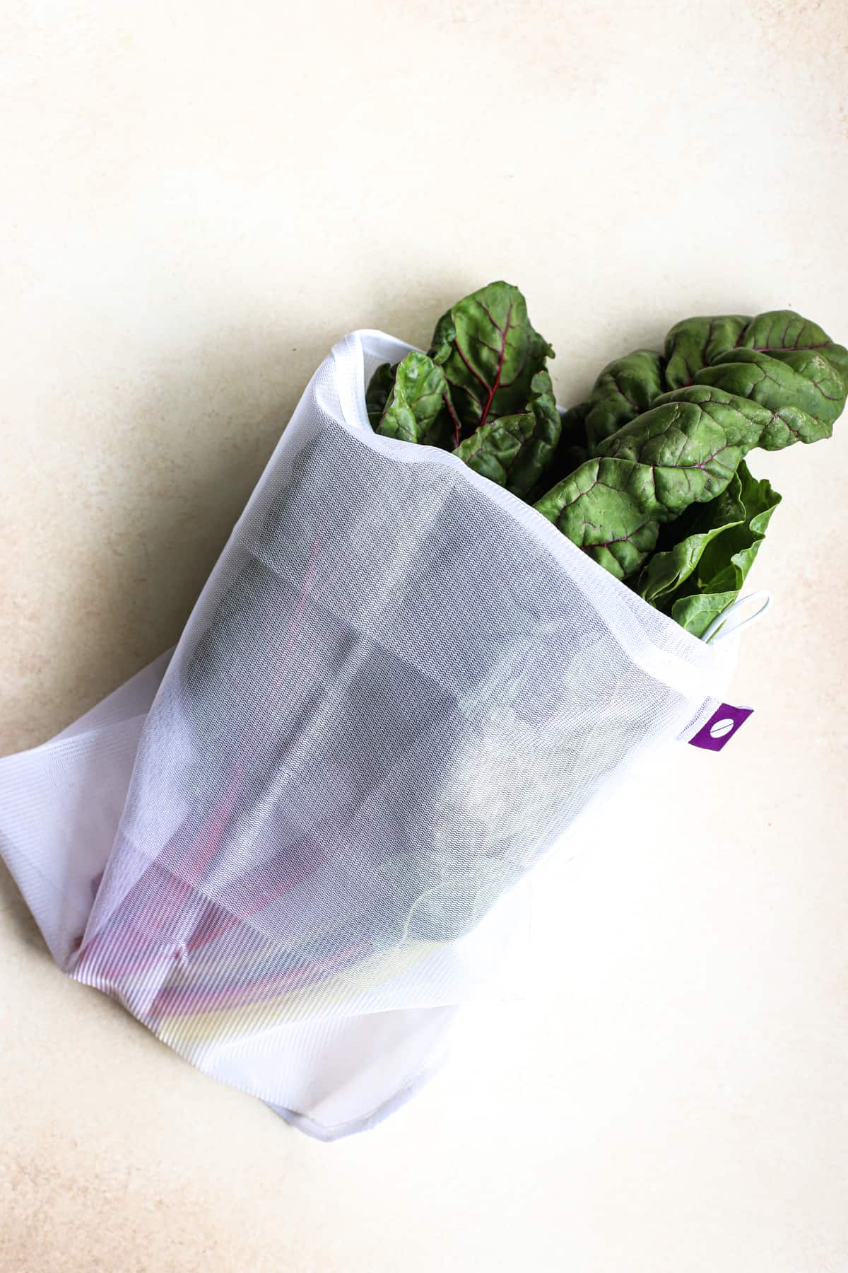 Swiss chard in white reusable produce bag, to show what a CSA is and might include