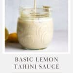 Creamy lemon tahini sauce in a small jar with sauce dripping from spoon.