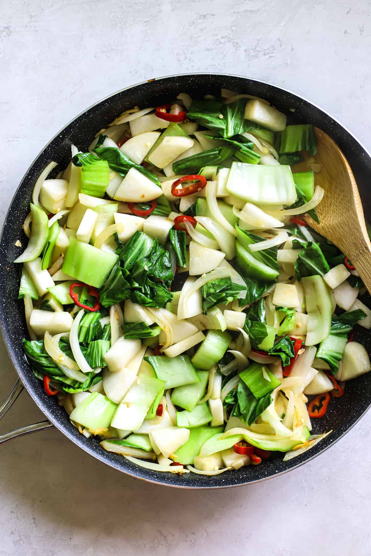 Pad pak veggies in large sauté pan with bamboo spoon