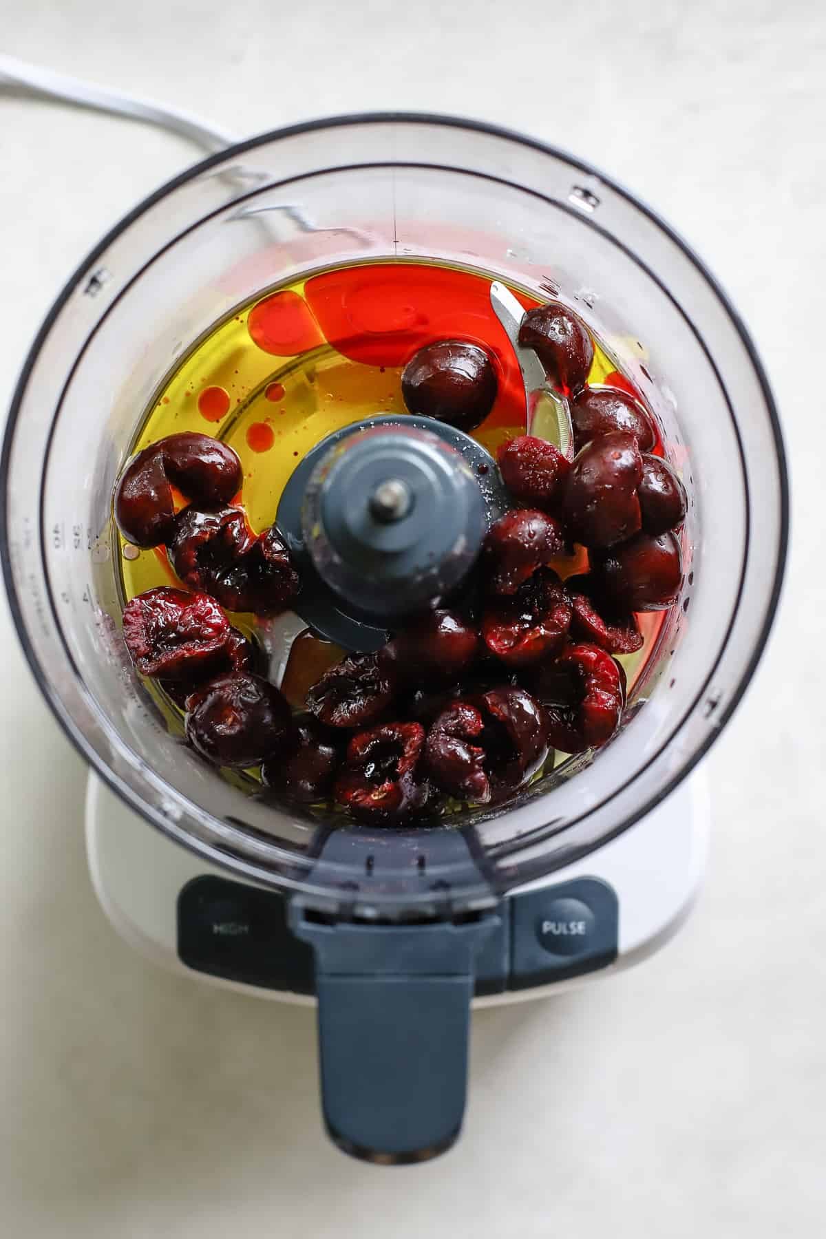 Cherries, olive oil, vinegar, and salt in food processor before being blended into vinaigrette.