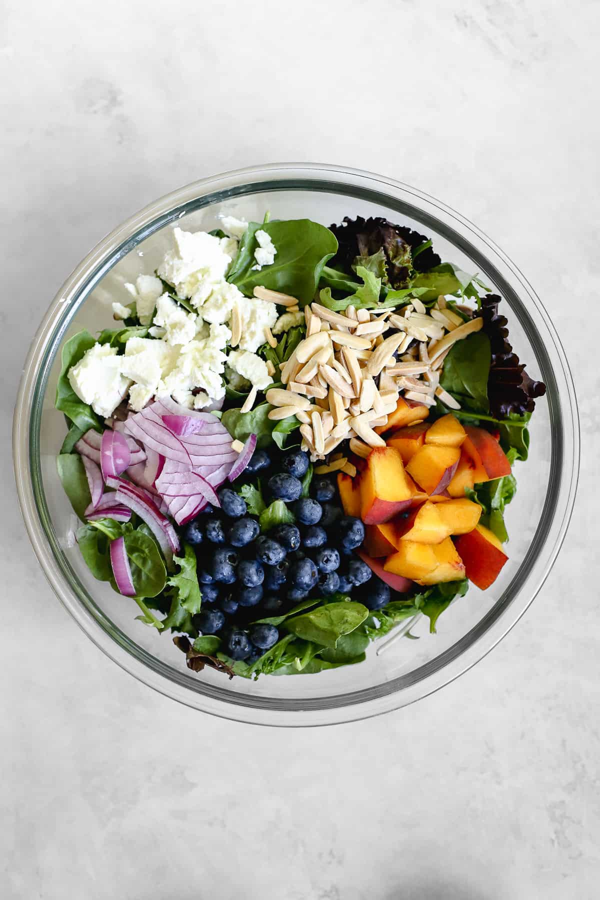 Peach blueberry salad ingredients in clear glass bowl