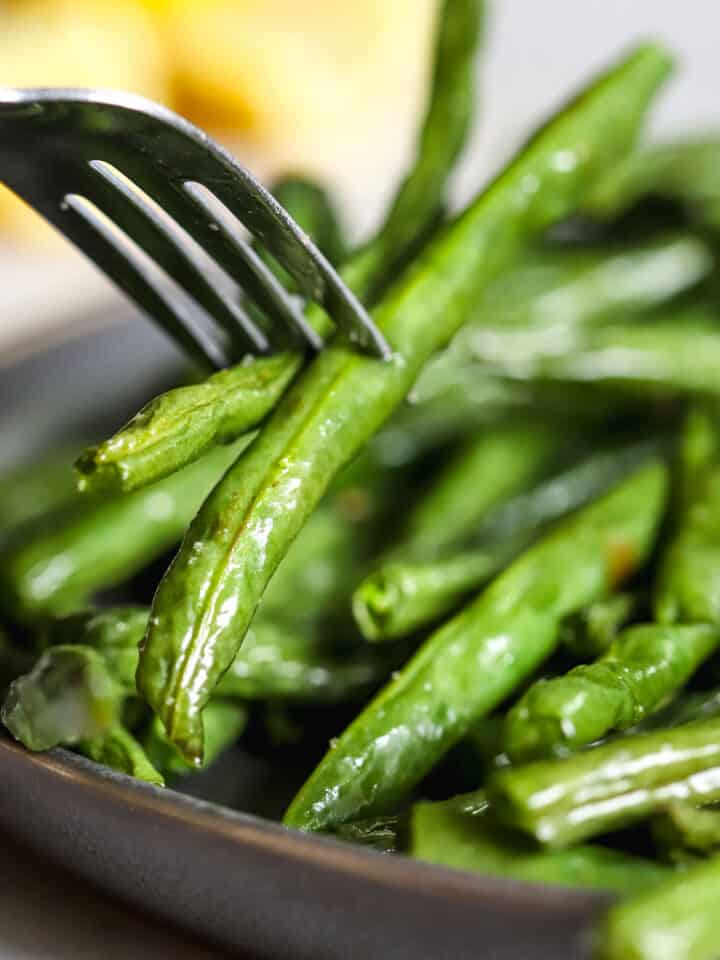 Air fryer green beans being speared with a fork