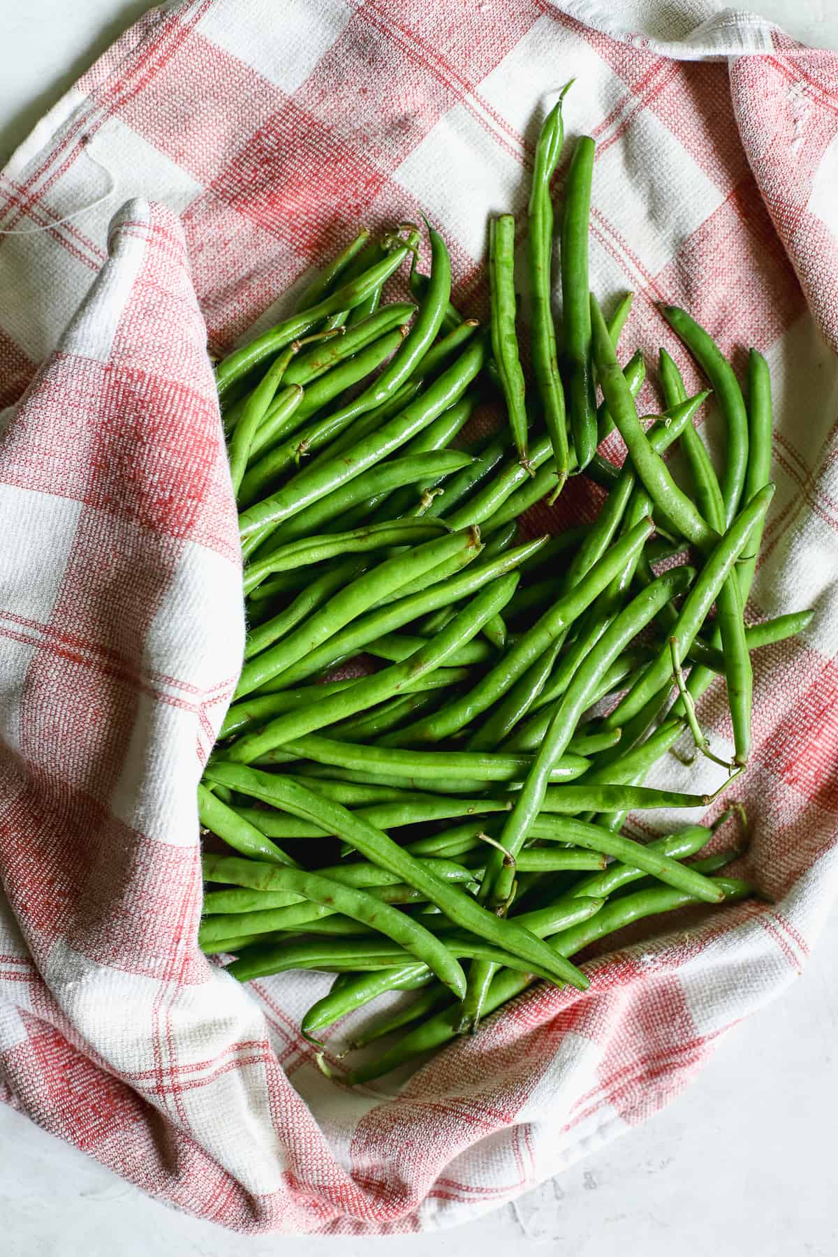 Drying fresh green beans on red and white towel.