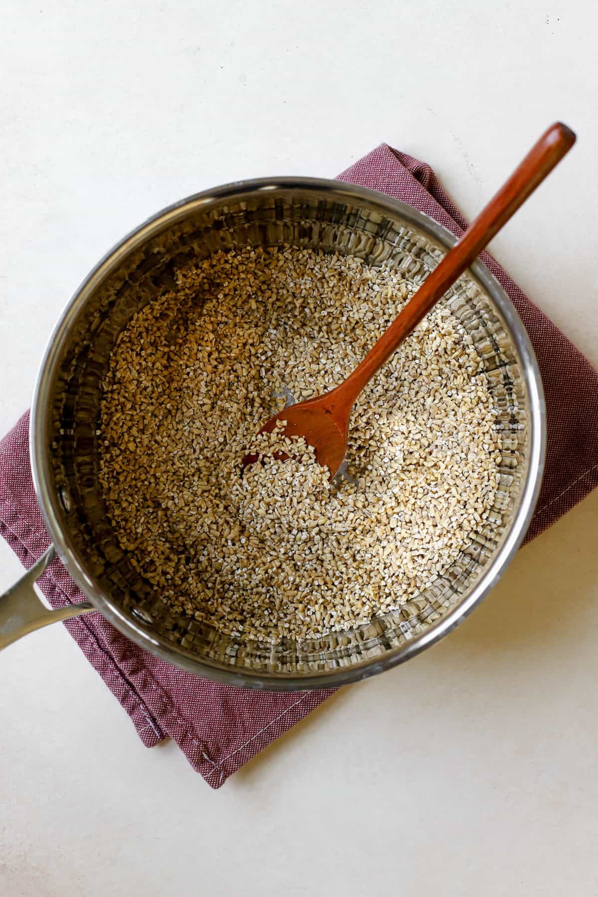 Steel cut oats toasting in saucepan with wooden spoon