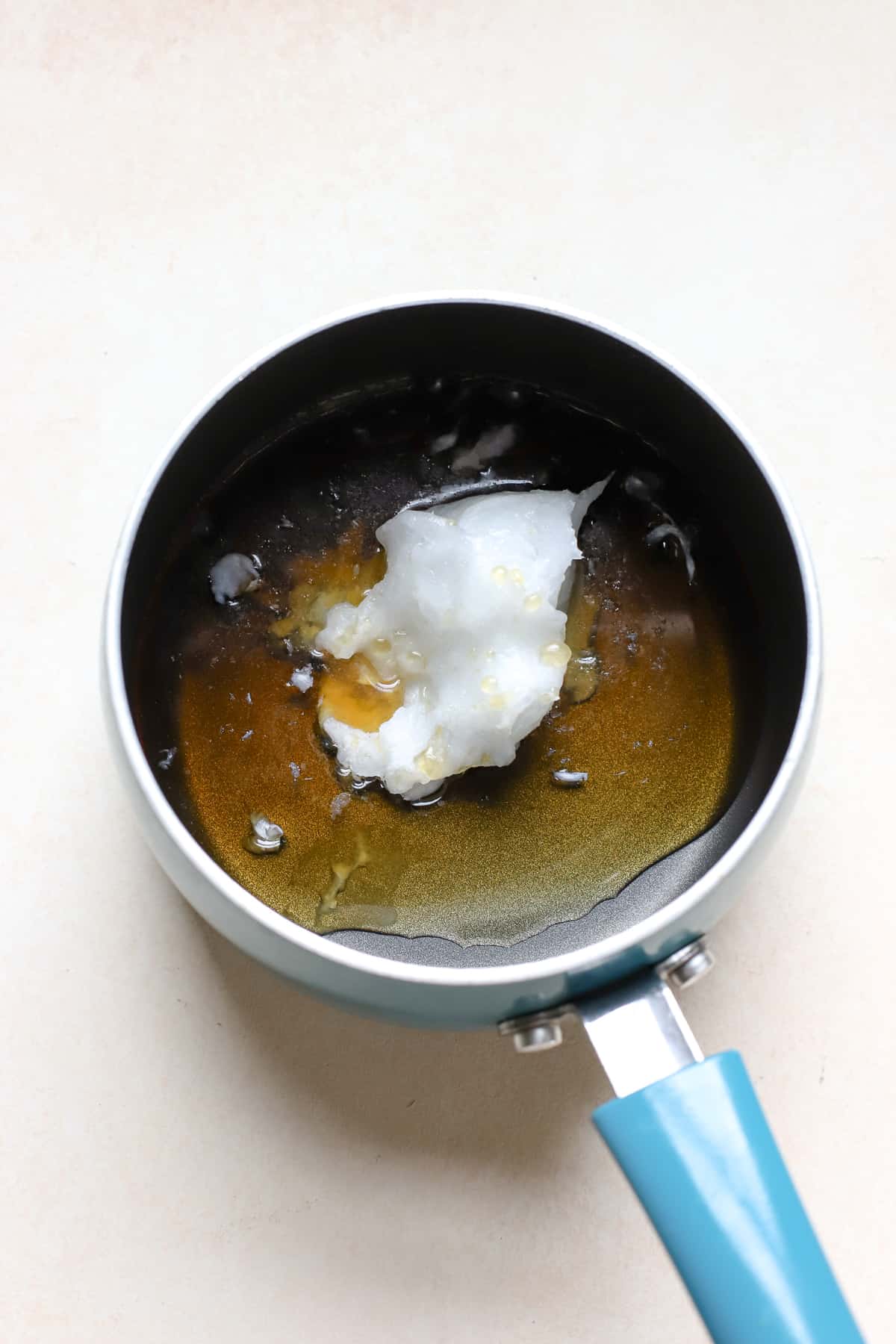 Maple syrup and coconut oil in small blue pot to be heated and mixed together for granola recipe.