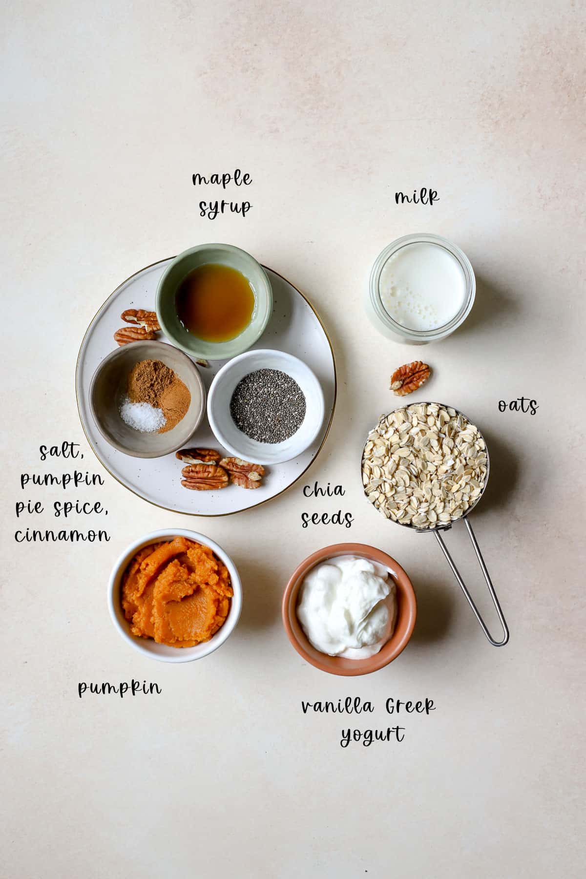 Ingredients including oats, chia seeds, salt, pumpkin pie spice, cinnamon, milk, vanilla Greek yogurt, pumpkin, maple syrup, and pecans
