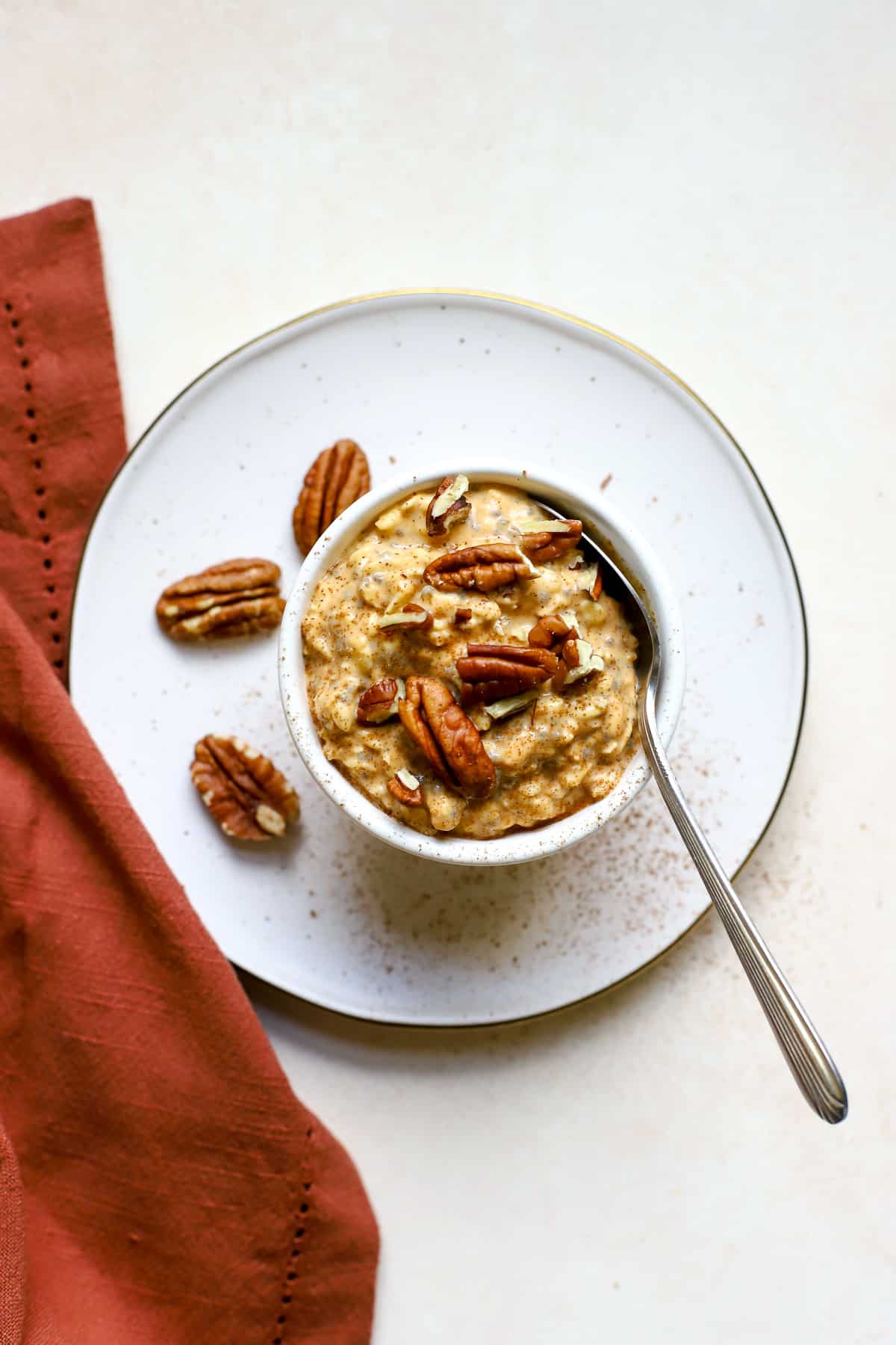 Pumpkin pie overnight oats in small white bowl topped with pecans.